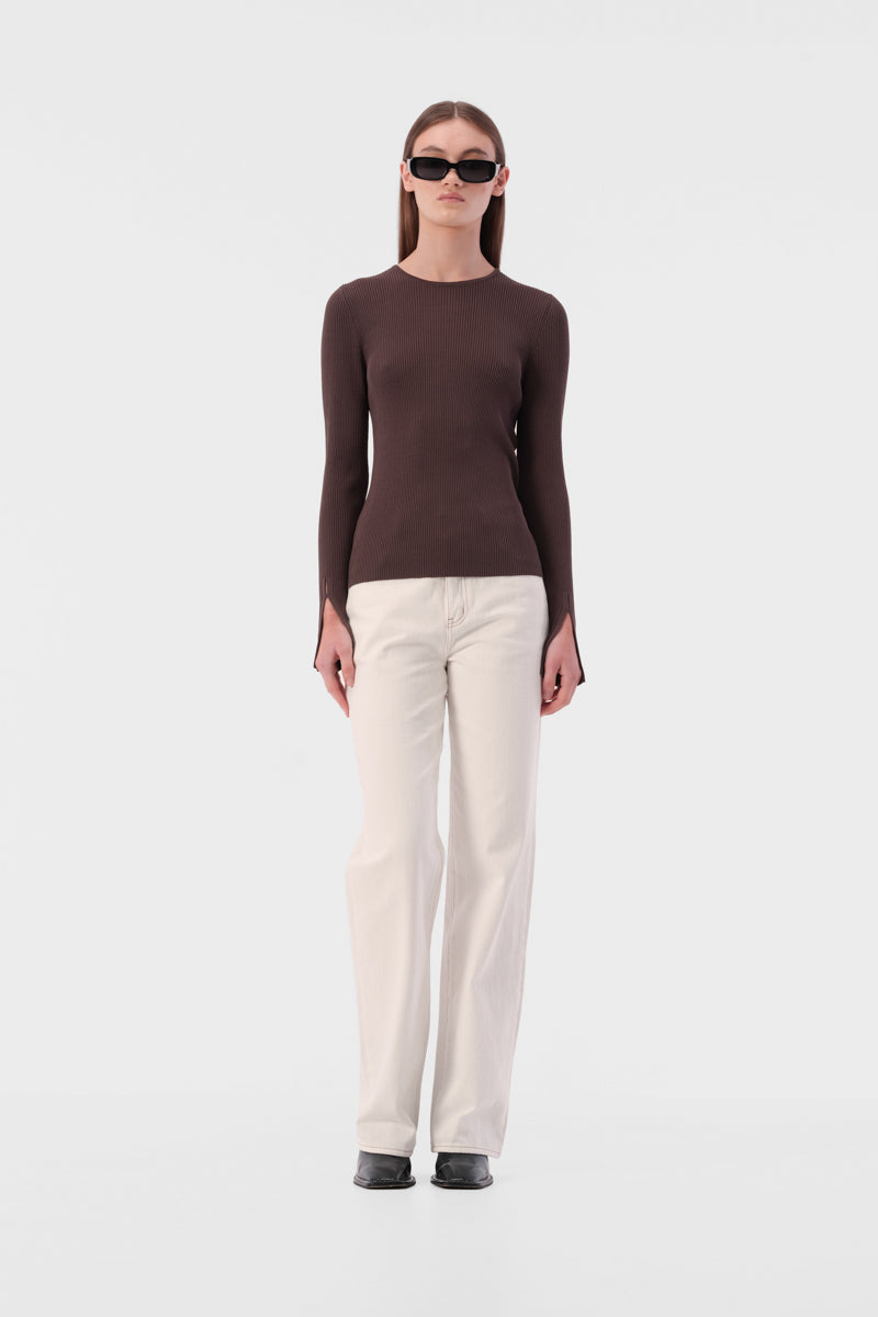 Slim fit knit top with round neckline and ribbed texture. Full length sleeve with split hem.