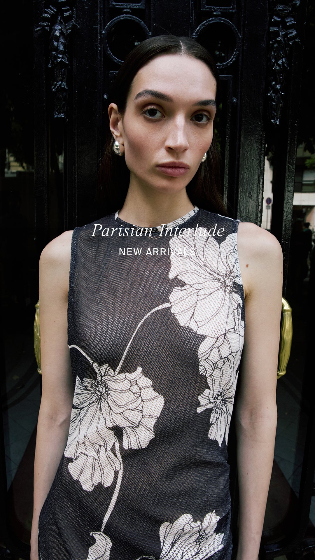 Woman wearing a brown dress with white floral patterns in front of a dark background