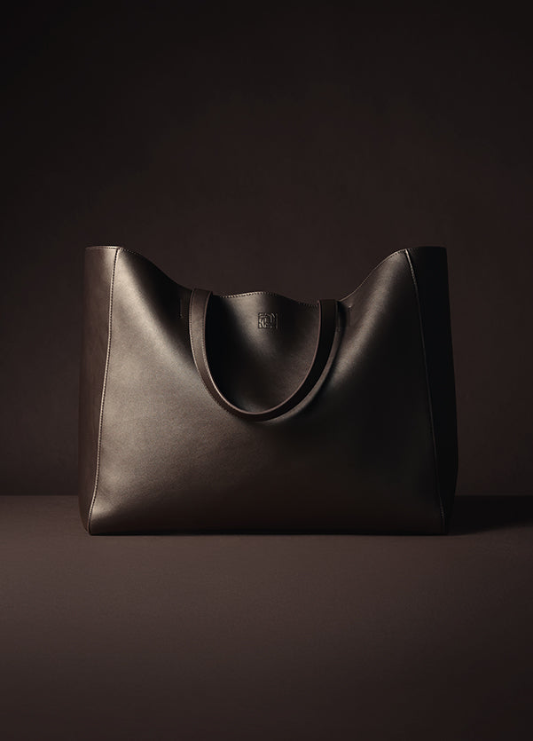 Brown leather tote bag on a dark background
