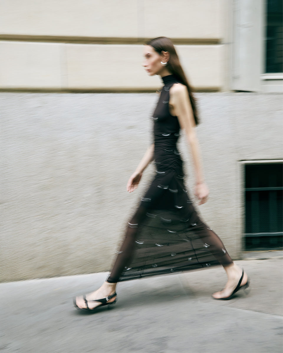Woman in a black dress walking on a street with a blurred background