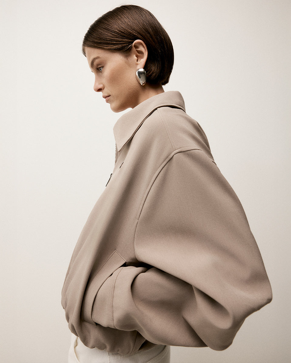 Woman wearing a beige coat against a plain background