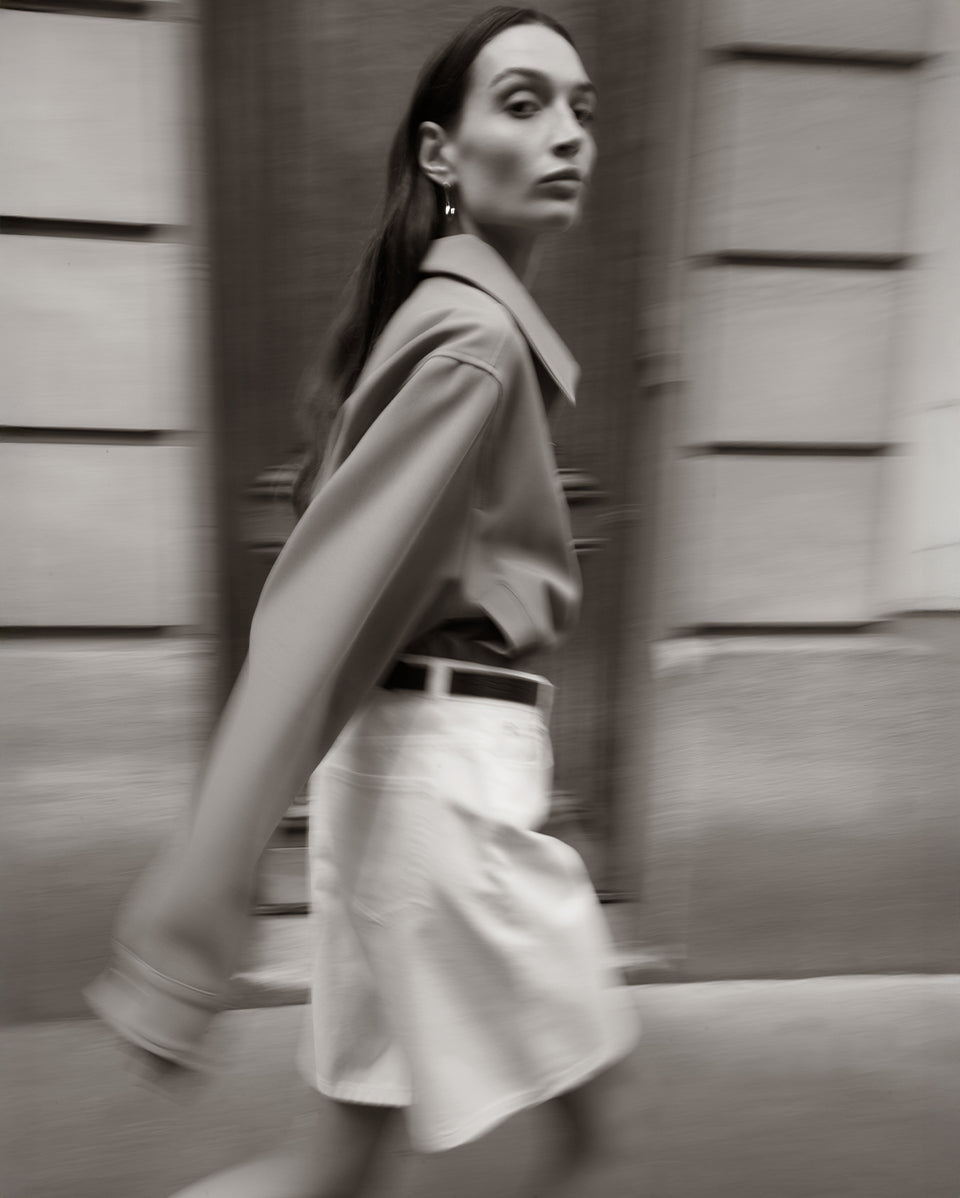 Woman walking past a wooden wall in a monochrome setting