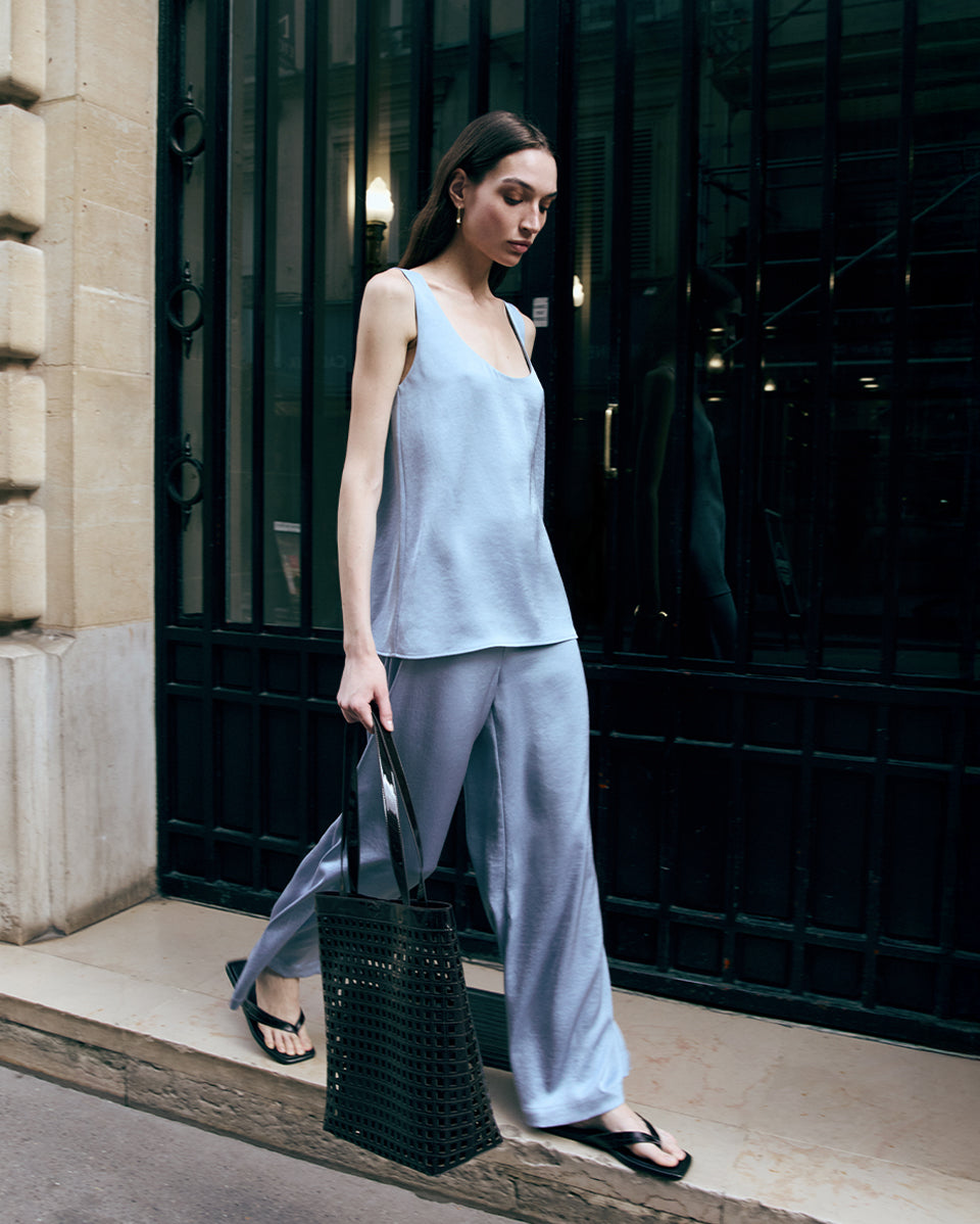 Woman in light blue outfit holding a brown bag outside a building