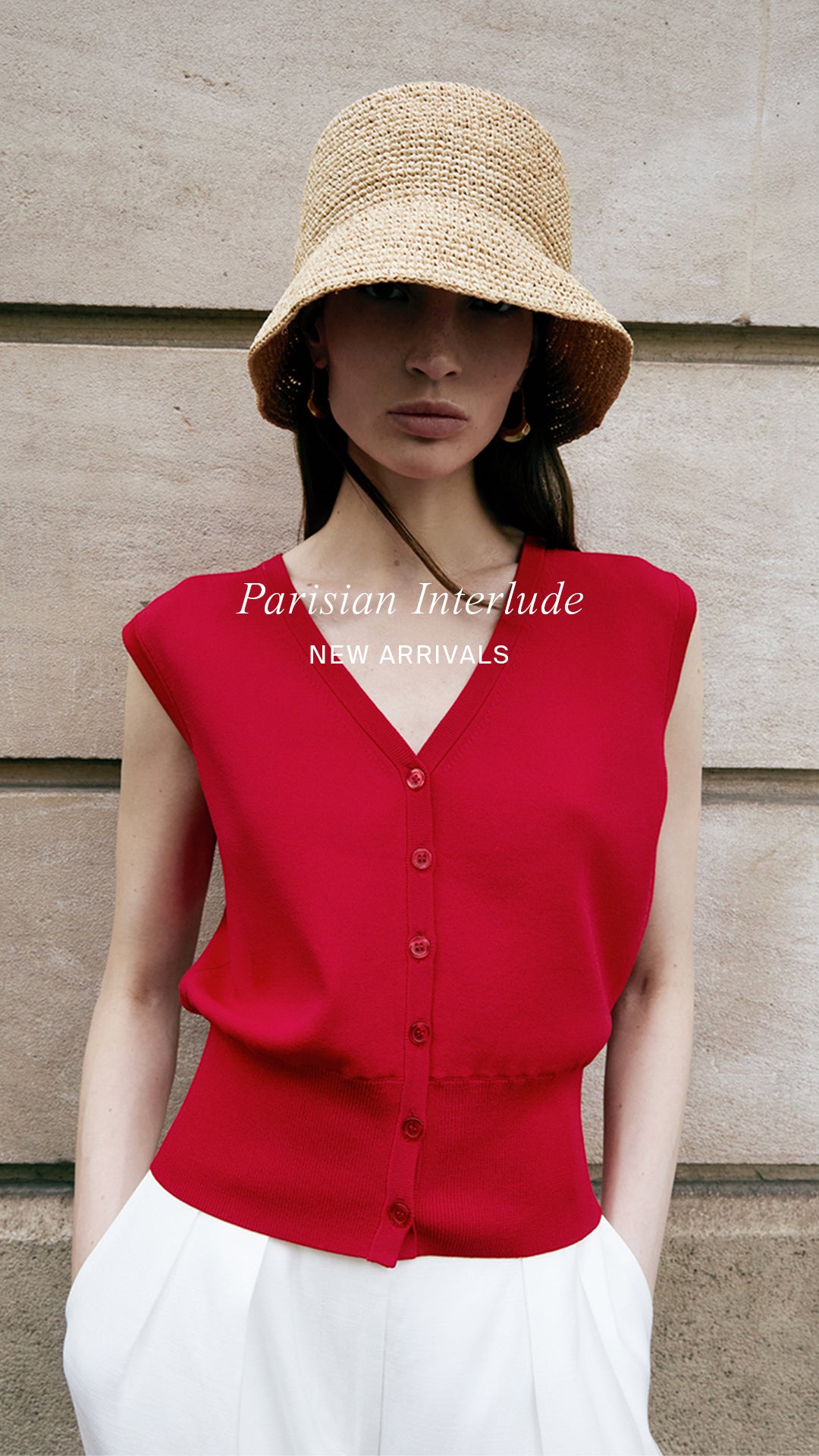 Woman wearing a red sleeveless top and straw hat against a stone background