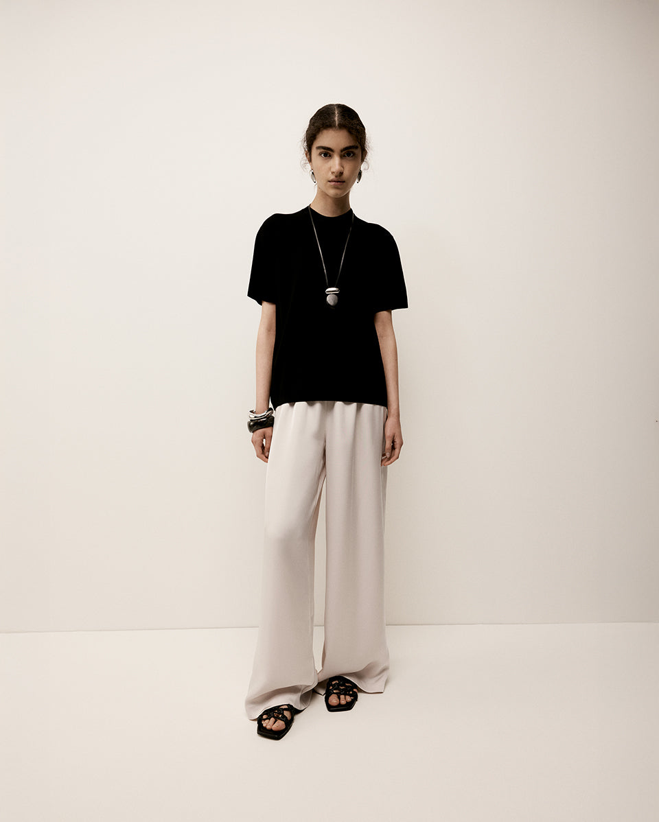 Person wearing a black t-shirt and beige pants on a white background